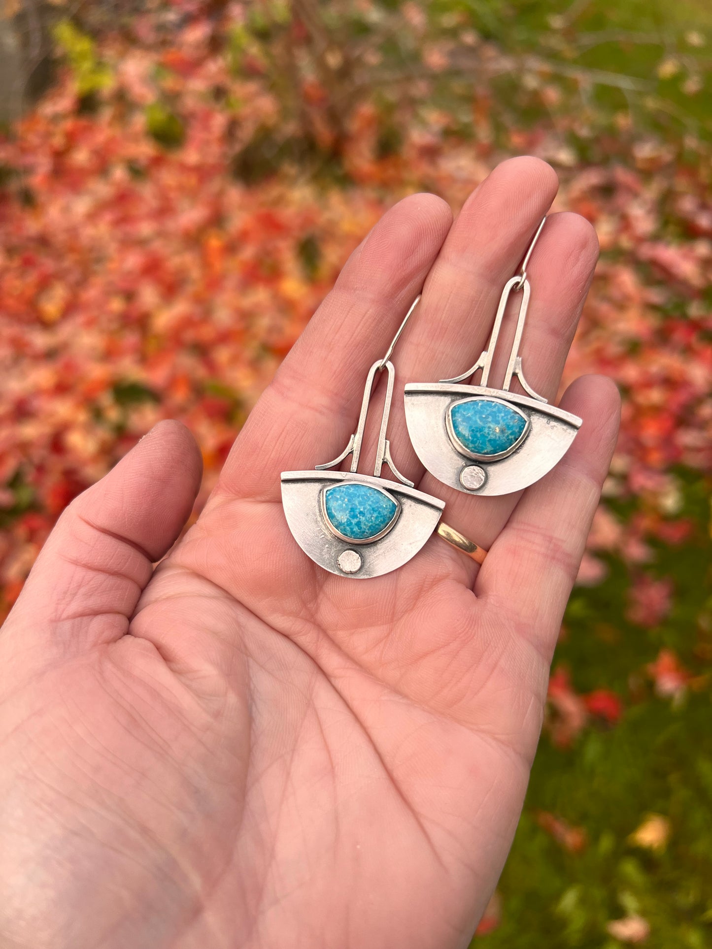 handcrafted earrings with Persian Turquoise. Framed in sterling silver, art deco in shape with a swooping half circle and elongated lines. They hang from a custom silver ear wire.&nbsp;