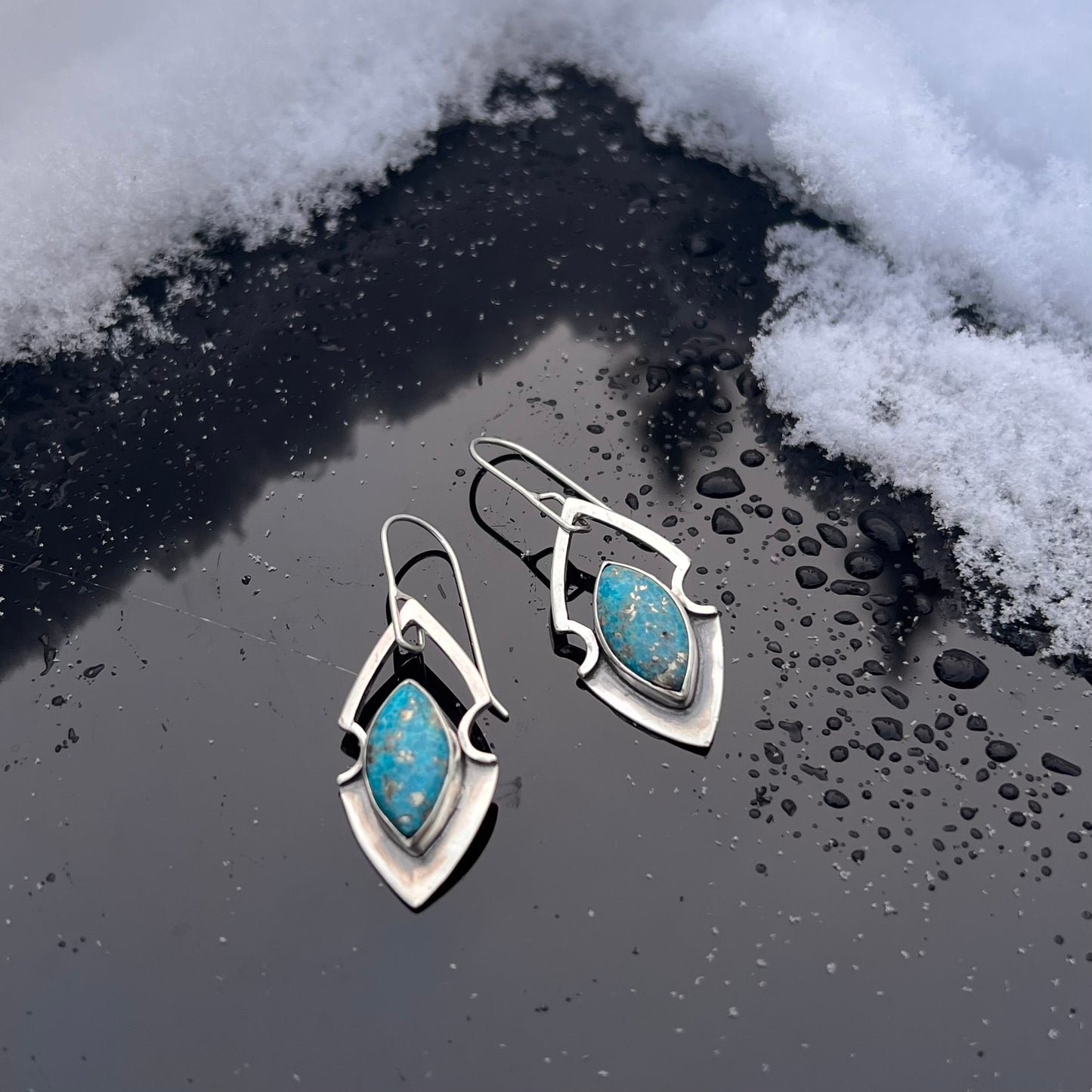 Persian Turquoise earrings with a delicate custom shape. The marquise cut turquoise has flecks of Pyrite, adding silver highlights to the ski blue stone. Light weight and easy to wear, they hang on a handcrafted ear wire.&nbsp; 